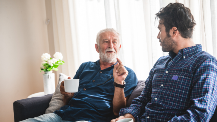 a senior men drinking coffee and having a conversation with his son