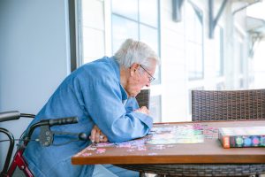 an old guy in front of a cross puzzle 