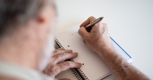 an old men writing in a notebook
